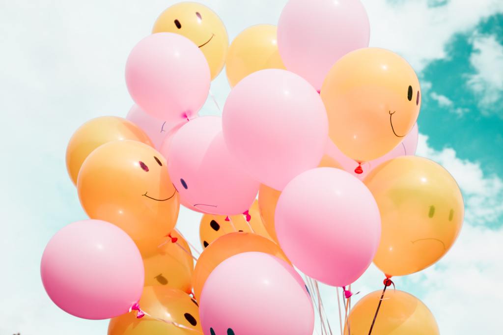 Pink and orange balloons, some with smiley faces painted on